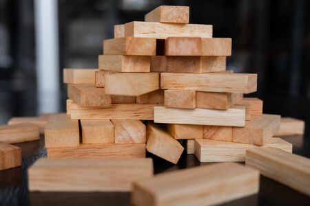 Wood block pile with architecture model with classic black tone background, Concept Risk management and strategy plan, growth business success process and team work.の写真素材