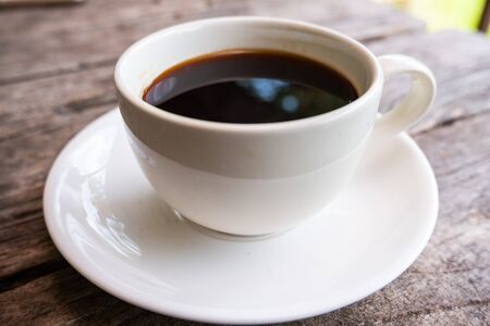 A cup of black coffee on the wooden table.