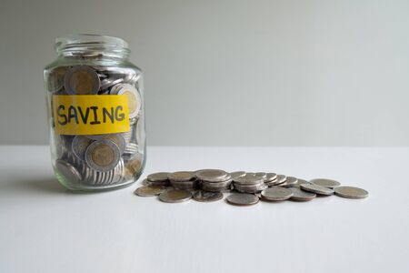 Glass piggy bank with coins pile, step up growing business to success and saving for retirement  concept.の写真素材