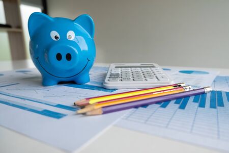 Blue piggy bank with pencils calculator and Graph, step up growing business to success and saving for retirement  concept.の写真素材