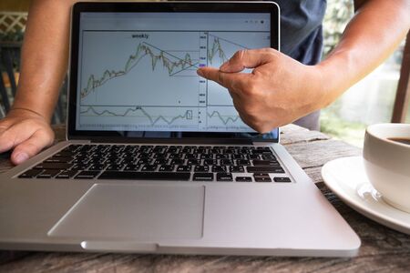 Trader man drink black coffee and pointing tactical move, strategy analysis of stock graph.の写真素材