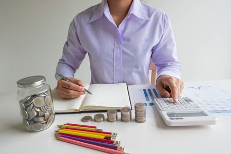 Business woman used calculator and record account with glass piggy bank, step up growing business to...