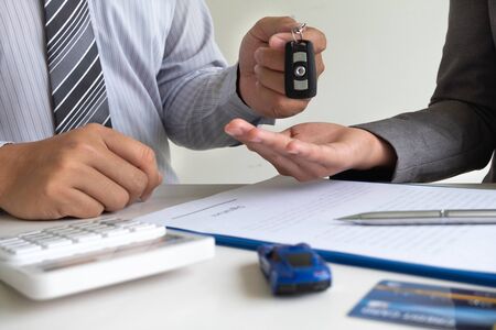Car dealership provides advice about insurance details and car rental information and delivers the keys after signing the rental contract.の写真素材