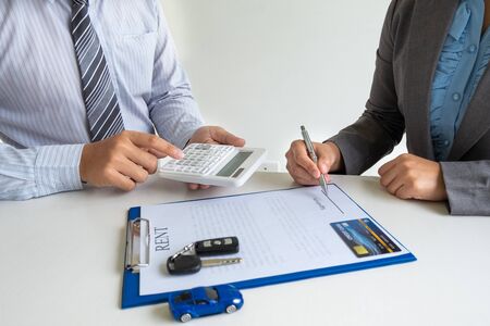 Car dealership provides advice about insurance details and car rental information and delivers the keys after signing the rental contract.の写真素材