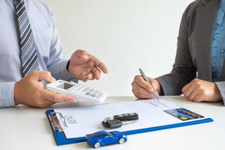 Car dealership provides advice about insurance details and car rental information and delivers the keys after signing the rental contract.の写真素材