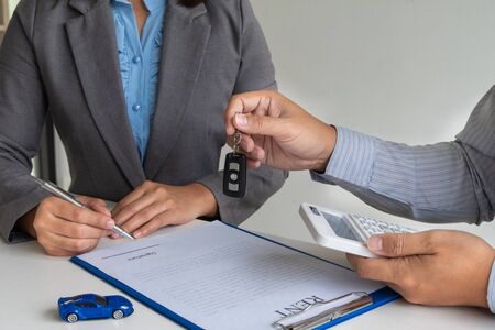 Car dealership provides advice about insurance details and car rental information and delivers the keys after signing the rental contract.の写真素材