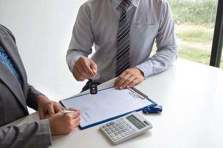 Car dealership provides advice about insurance details and car rental information and delivers the keys after signing the rental contract.の写真素材
