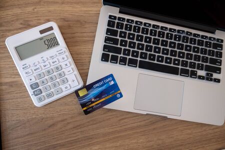 Credit cards, calculators and laptops are on the desk.の写真素材