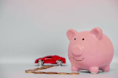 Piggy bank with coins on a white background to save on car buying, the concept of  and buying cars.の写真素材