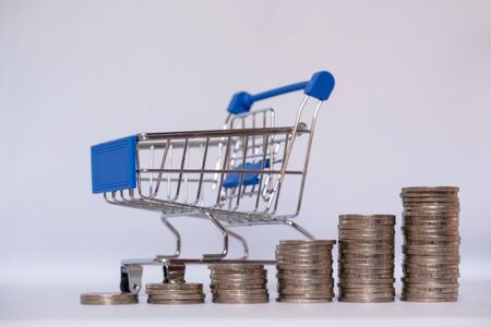 A small cart with a coin on a white background leading to growth to success, saving, saving concept.の写真素材