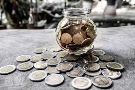 Glass jar piggy bank with coins. Plan your savings, run a growing business for success and save for retirement.の写真素材