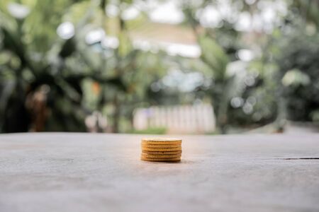 Golden coins pile on wooden table with the natural background, step up growing business to success and saving for retirement concept.の写真素材