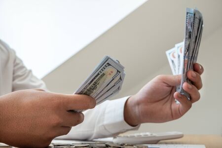 Businessmen holding dollars and coins in front, calculate graphs to save money, expand successful...