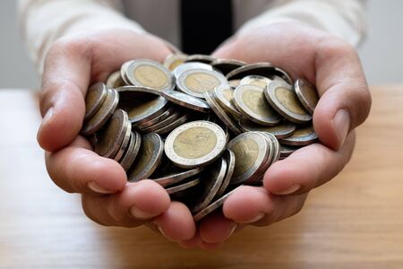 The hands of businessmen who hold coins to save money, expand a growing business to success and save...