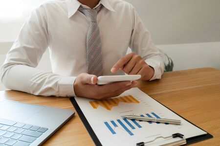 A business man is sitting at a desk and calculating financial graphs about real estate investment...