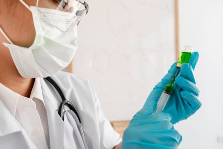 Medical scientists hold a liquid vaccine bottle and syringe in a chemical laboratory Scientific...