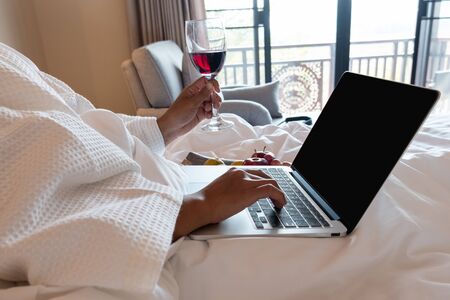The hand of Young woman that hold wine glass And Sit play laptop In a luxurious room Ready Fruit.の写真素材