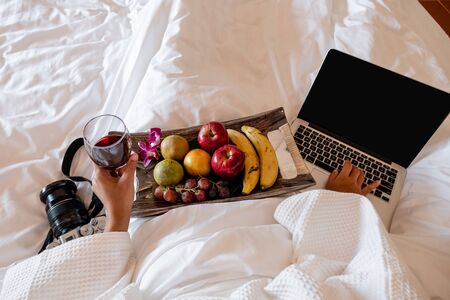 The hand of Young woman that hold wine glass And Sit play laptop In a luxurious room Ready Fruit.の写真素材