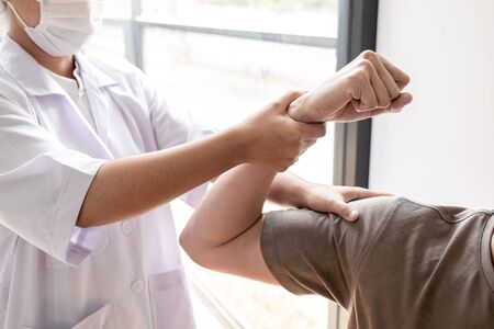 Female physiotherapists provide assistance to male patients with elbow injuries examine patients in rehabilitation centers. Physiotherapy concepts.の写真素材