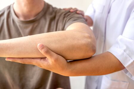 Female physiotherapists provide assistance to male patients with elbow injuries examine patients in rehabilitation centers. Physiotherapy concepts.の写真素材