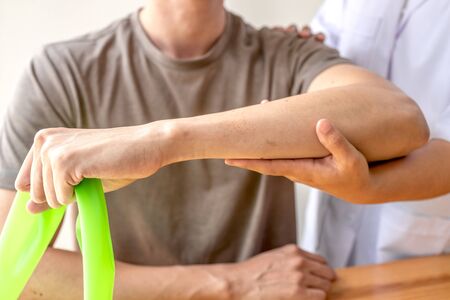 Female physiotherapists provide assistance to male patients with elbow injuries examine patients in rehabilitation centers. Physiotherapy concepts.の写真素材