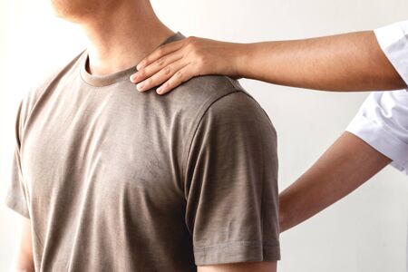 Female physiotherapists provide physical assistance to male patients with shoulder injuries massage their shoulders for muscle recovery in the rehabilitation center. Physiotherapy concepts.の写真素材