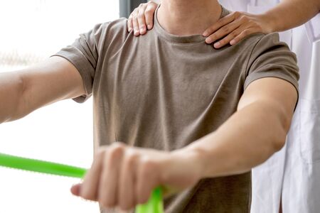 Female physiotherapists provide physical assistance to male patients with shoulder injuries massage their shoulders for muscle recovery in the rehabilitation center. Physiotherapy concepts.の写真素材