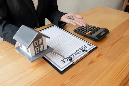The hand of a home insurance agent is holding a modelhome to protect the safety for customers buyers.の写真素材