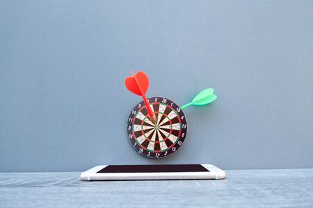 The small dartboard and the arrow located with telephone represent successful business goals concept.の写真素材