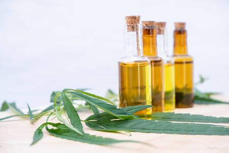 Glass bottle with extracting CBD oil formula and hemp leaf on a wooden floor. Medical cannabis concept.の写真素材