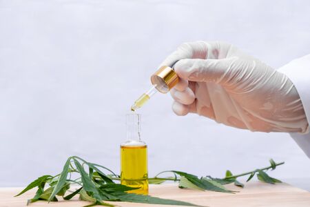 Glass bottle with extracting CBD oil formula and hemp leaf on a wooden floor. Medical cannabis...