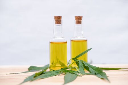 Glass bottle with extracting CBD oil formula and hemp leaf on a wooden floor. Medical cannabis...