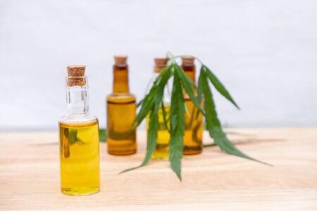 Glass bottle with extracting CBD oil formula and hemp leaf on a wooden floor. Medical cannabis concept.の写真素材