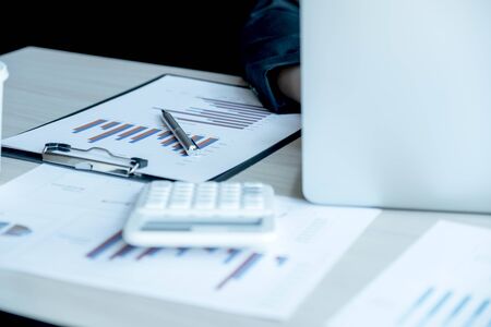 business man is sitting at a desk and calculating financial graph that show results.の写真素材