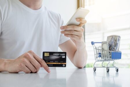Young man people who hold credit cards and smartphones for online shopping and making payments Internet.の写真素材