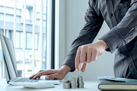 A man put a coin on a pile of coins to grow, step into a successful and economical business for...