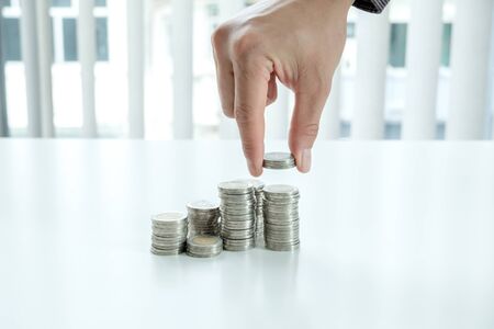 A man put a coin on a pile of coins to grow, step into a successful and economical business for...