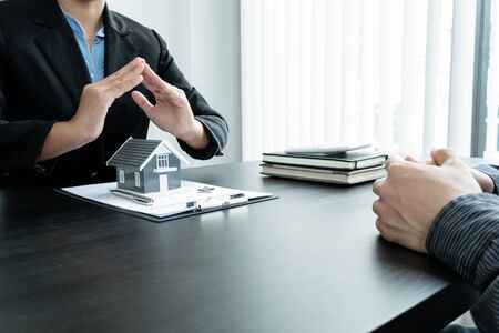 The house is covered by the hands of a real estate agent to protect the house for customers, homebuyers, insurance, ready give to with new owner. Home insurance sales concept.の写真素材