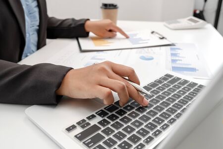 The hands of a male businesswoman are analyzing and calculating the annual income and expenses in a...