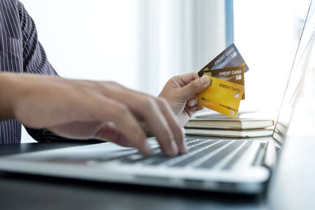 The businessman's hand is holding a credit card and using a laptop for online shopping and internet payment in the office.の写真素材