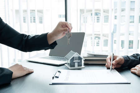 Real estate agent broker hand over the house key to the new owner after completing the signing...