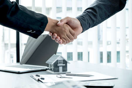 A real estate agent and clients shake hands after completing the home insurance contract negotiation...