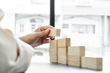 Hands of businesswomen playing wooden block game. Concept Risk of management and strategy plans for business growth and success.の写真素材