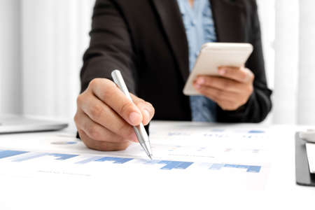 The hands of a male businesswoman are analyzing and calculating the annual income and expenses in a...