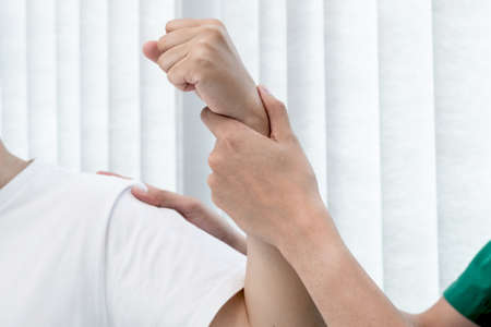 male physiotherapists provide assistance to male patients with elbow injuries to examine patients in...
