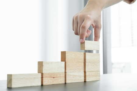 Hands of businesswomen playing wooden block game. Concept Risk of management and strategy plans for business growth and success.の写真素材