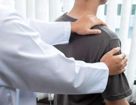 Female physiotherapists provide physical assistance to male patients with shoulder injuries massage their shoulders for muscle recovery in the rehabilitation center. Physiotherapy concepts.の写真素材