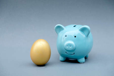 Blue color piggy bank with golden eggs, step up the growing business to success and saving for retirement concept.の写真素材