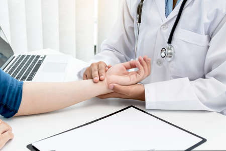 The doctor measures the wrist pulse, the heartbeat of the patient, and discusses health care closely.の写真素材