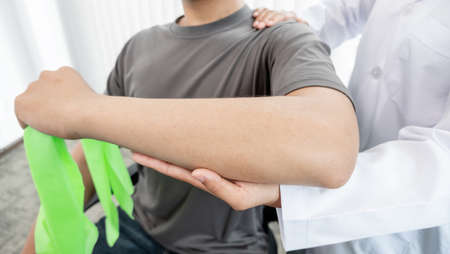 Female physiotherapists provide assistance to male patients with elbow injuries to examine patients in rehabilitation centers. Rehabilitation physiotherapy concept.の写真素材